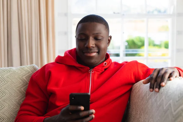 Усміхаючись Афроамериканцем Він Сидить Вдома Дивані Користуючись Смартфоном Інклюзивність Сімейне — стокове фото