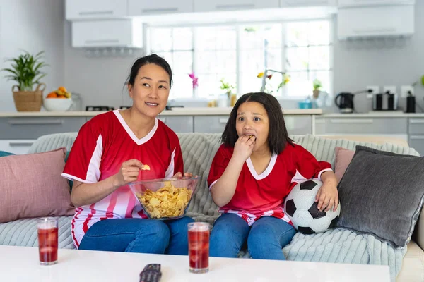 Aziatische Moeder Dochter Voetbalshirts Kijken Naar Voetbalwedstrijden Ondersteunen Eten Chips — Stockfoto