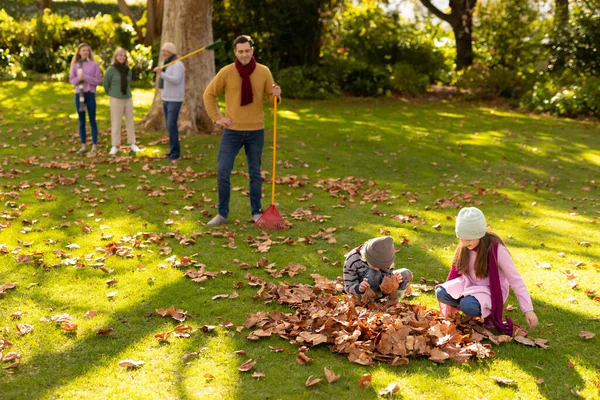 정원에서 나뭇잎을 까딱거리는 코카서스 가족의 질높은 시간을 보내는 — 스톡 사진