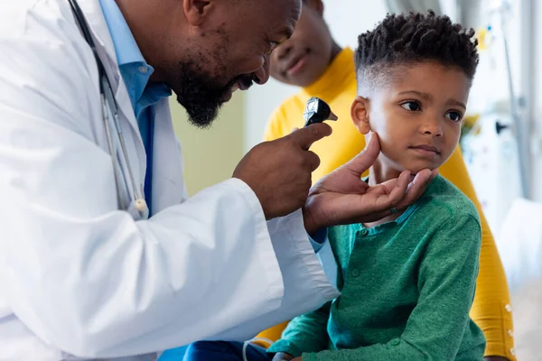 非裔美国男医生用耳镜检查男病人的耳朵 与母亲 医疗和保健服务 — 图库照片