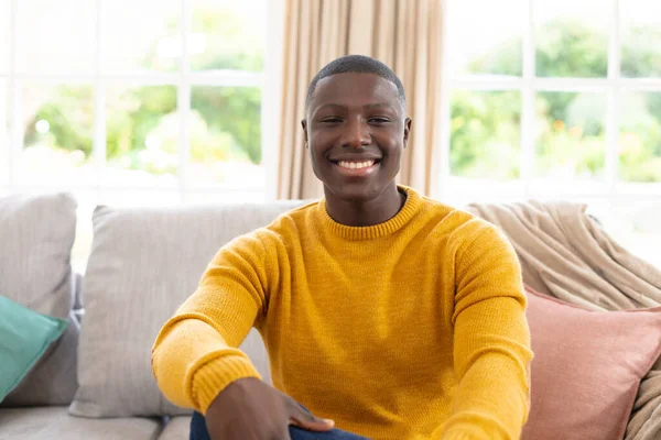 아프리카 미국인 남자의 사진이죠 소파에 웃으며 카메라를 봅니다 긍정적 집에서 — 스톡 사진