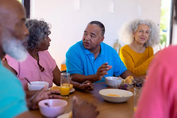 在养老院 多种族的老朋友在餐桌边谈论和吃着健康的早餐 辅助生活和退休概念 — 图库照片