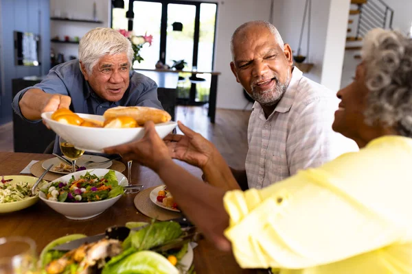 Усміхнений Старший Чоловік Дає Жінці Хліб Обідаючи Обіднім Столом Будинку — стокове фото