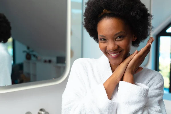 バスルームでバスローブを着たアフリカ系アメリカ人の若いアフロ女性の笑顔の肖像画 スペースをコピーします 変更されていない リラクゼーション 甘やかす デトックス ボディケアと健康の概念 — ストック写真