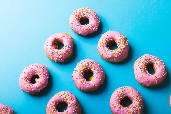 Bovenaanzicht Van Verse Donuts Met Sprinklers Tegen Een Blauwe Achtergrond — Stockfoto