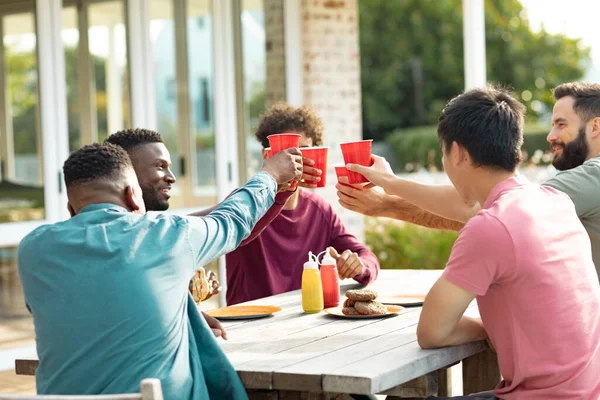 快乐的多种族男性朋友在院子里的餐桌边敬酒 社交活动 享乐及周末活动概念 — 图库照片