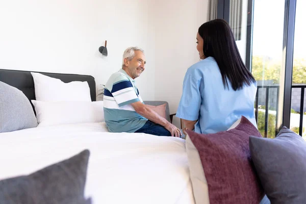Çift Irklı Kadın Sağlık Çalışanı Evdeki Yatakta Oturan Kafkasyalı Son — Stok fotoğraf