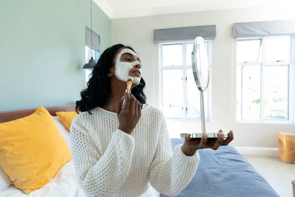 Evde Yatağın Üzerine Yüz Kremi Sürerken Aynaya Bakan Melez Genç — Stok fotoğraf