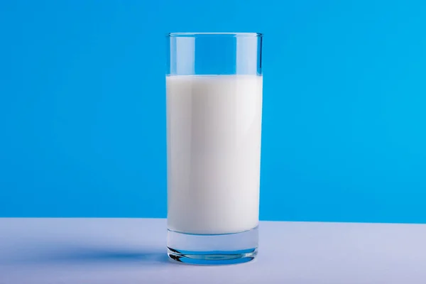 コピースペースのある青の背景を背景にテーブルの上にミルクガラスのクローズアップ 変更されていない 食べ物 飲み物 スタジオで撮影された健康的な食品コンセプト — ストック写真