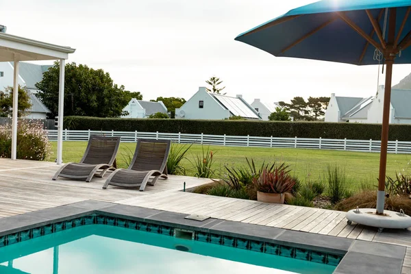 Prázdné Lehátka Deštník Bazénu Domy Solárními Panely Střeše Proti Obloze — Stock fotografie