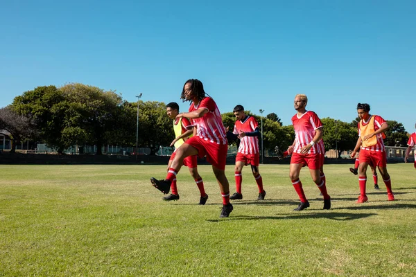 Jogadores Multirraciais Masculinos Vestindo Uniformes Vermelhos Correndo Exercitando Contra Céu — Fotografia de Stock
