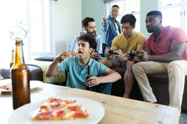 多种族男性朋友在客厅里玩电子游戏 享受啤酒和披萨 复制空间 游戏控制 娱乐和周末活动 — 图库照片