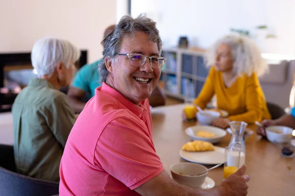一个快乐的高加索老人在餐桌与多种族朋友共进早餐的画像 退休家庭 辅助生活理念 — 图库照片