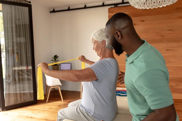 Afroameričtí Mužští Fyzioterapeuti Pomáhají Starší Ženě Cvičit Odbojovými Pásmy Zdravotní — Stock fotografie