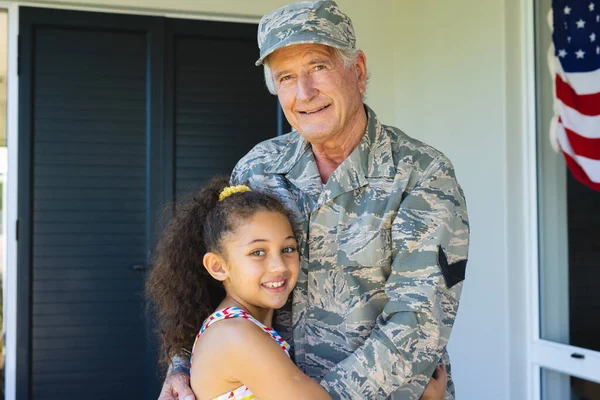 stock image Portrait of smiling multiracial military grandfather in camouflage clothing embracing granddaughter. Unaltered, family, togetherness, childhood, military, patriotism and homecoming.