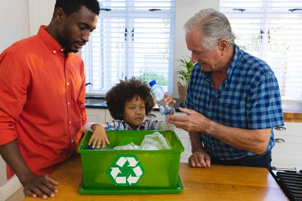 多种族的祖父和父亲教男孩通过把塑料瓶扔进垃圾桶来回收废物 未改变 在一起 未改变 环境保护 — 图库照片