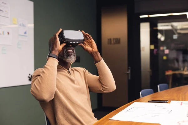 Mature african american businessman using virtual reality simulator at office. Unaltered, creative business, workplace, occupation, futuristic and modern technology.