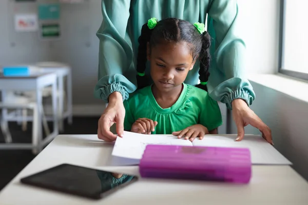 Caucasian Young Female Teacher Assisting African American Elementary Girl Studying — Stock Photo, Image