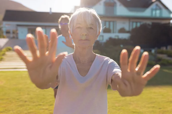 老人ホームに向かい庭で運動をしながら手を伸ばしているアジア系の先輩女性の姿 変更されていない サポート 生活支援 フィットネスやアクティブなライフスタイルの概念 — ストック写真