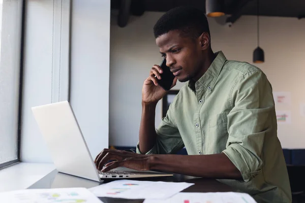 Determinado Empresário Afro Americano Falando Por Telefone Enquanto Trabalhava Laptop — Fotografia de Stock