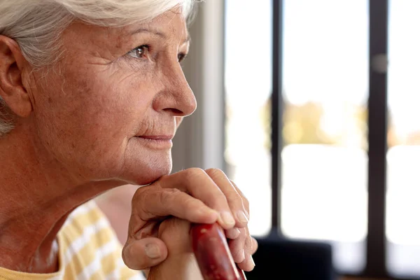 一位白种人老年妇女微笑着拿着一根手杖坐在家里的沙发上 老年生活方式和生活概念 — 图库照片
