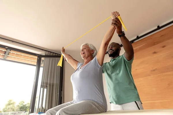 Африканский Американский Физиотерапевт Мужчина Помогает Пожилой Женщине Тренироваться Полосами Сопротивления — стоковое фото