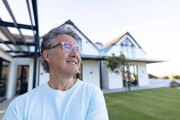 庭の家に目を背けて眼鏡をかけて笑う白人の先輩 コピースペース 変更されていない サポート 生活や退職の家を支援 — ストック写真