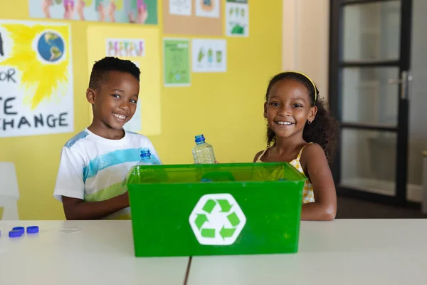 在学校桌上摆着回收容器的笑着的非洲小学生的画像 环境清理 可持续生活方式和学校概念 — 图库照片