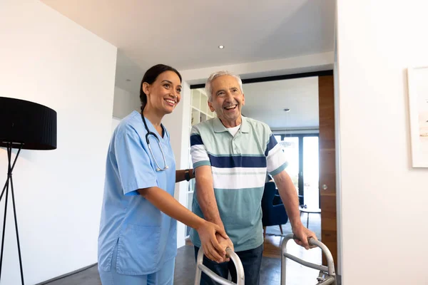 Πολυφυλετική Φυσιοθεραπεύτρια Που Βοηθάει Έναν Χαρούμενο Ηλικιωμένο Άντρα Περπατήσει Τον — Φωτογραφία Αρχείου