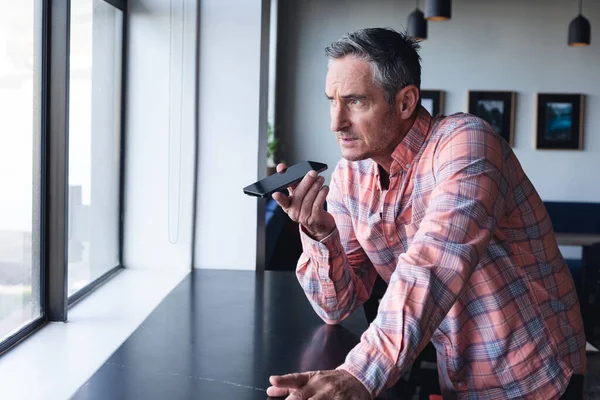 Kafkasyalı Yetişkin Adamı Yaratıcı Ofisin Penceresinden Akıllı Telefon Hoparlörüyle Konuşuyor — Stok fotoğraf