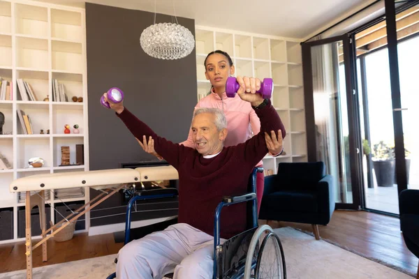 Çift Irklı Fizyoterapist Tekerlekli Sandalyede Oturan Yaşlı Beyaz Adama Yardım — Stok fotoğraf