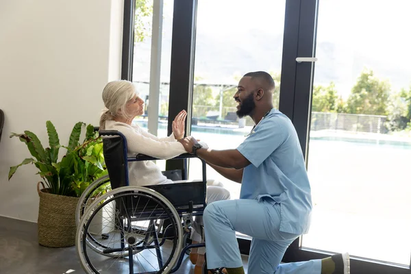 アフリカ系アメリカ人男性の健康労働者が車椅子に座っている白人のシニア女性を支援している 医療と定年退職シニアライフスタイルの概念 — ストック写真