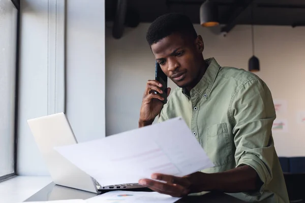 Zdeterminowany Afrykański Biznesmen Rozmawiający Przez Telefon Podczas Badania Dokumentów Biurze — Zdjęcie stockowe