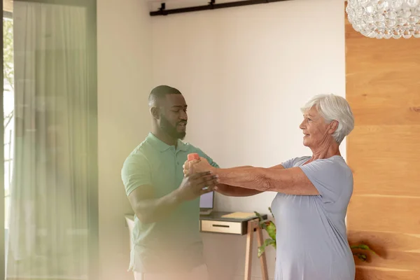 Afrikanisch Amerikanischer Männlicher Physiotherapeut Hilft Kaukasischer Seniorin Beim Turnen Mit — Stockfoto