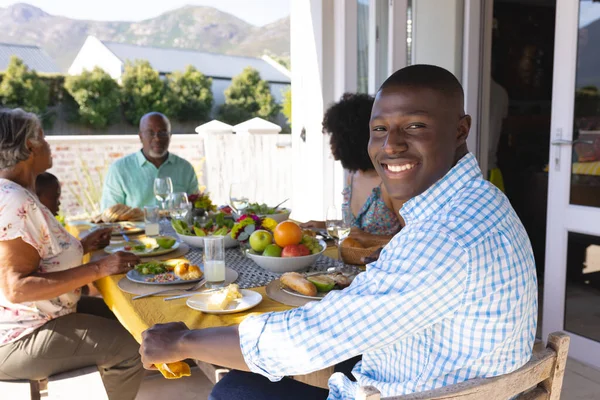 与多种族多代家庭在餐桌共进午餐的笑脸年轻人的画像 生活方式和退休 — 图库照片
