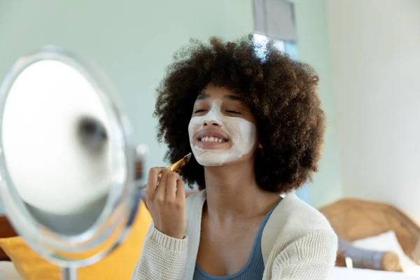 Yüzüne Güzellik Kremi Sürerken Aynaya Bakan Melez Bir Kadın Mutlu — Stok fotoğraf