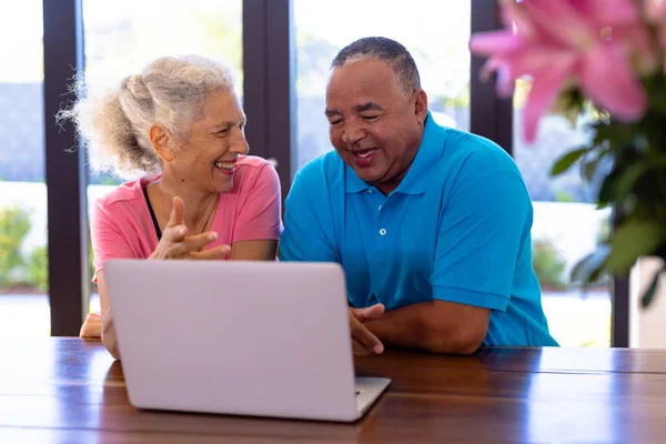 快乐的老男人和白种人坐在桌旁 一边看笔记本电脑上的视频 无线技术 互联网 辅助生活 — 图库照片