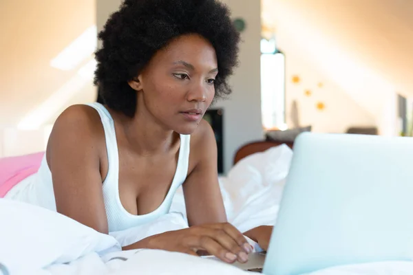 アフリカ系アメリカ人の若いアフロ女性がベッドルームのベッドの上に横たわっている間 ノートパソコンを使用して スペースをコピーします 変化のない ライフスタイル テクノロジーの概念 — ストック写真