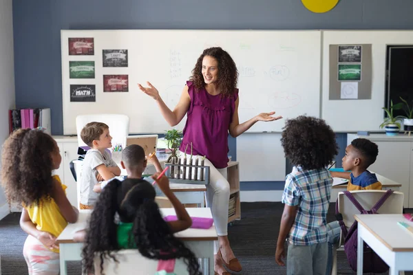 理科の授業では 白人の若い女性教師を見ている多人種の小学生 変化のない教育子供時代教育学習科学学校の概念 — ストック写真