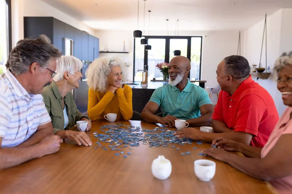 多种族老年朋友坐在养老院的木桌边玩拼图游戏 头脑风暴 在一起 辅助生活 — 图库照片