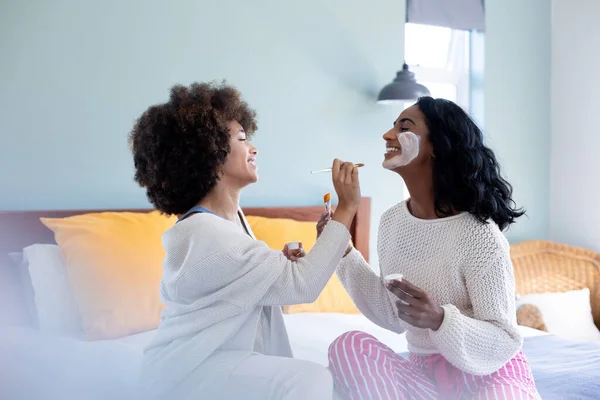 Afro Saçlı Melez Genç Bir Kadın Yatakta Otururken Arkadaşının Yüzüne — Stok fotoğraf