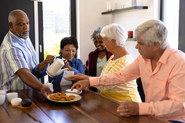 多种族快乐的老年男女朋友在养老院享用咖啡和饼干 不变食品 辅助生活和退休 — 图库照片