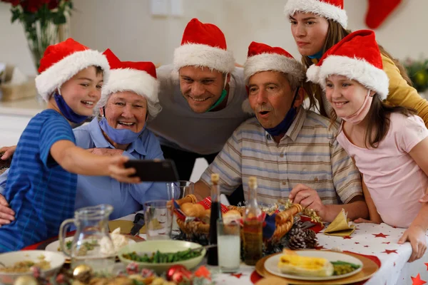 多代高加索家庭带着智能手机和微笑的自拍 戴着桑塔帽和面罩 优质家庭时间圣诞庆祝活动 — 图库照片