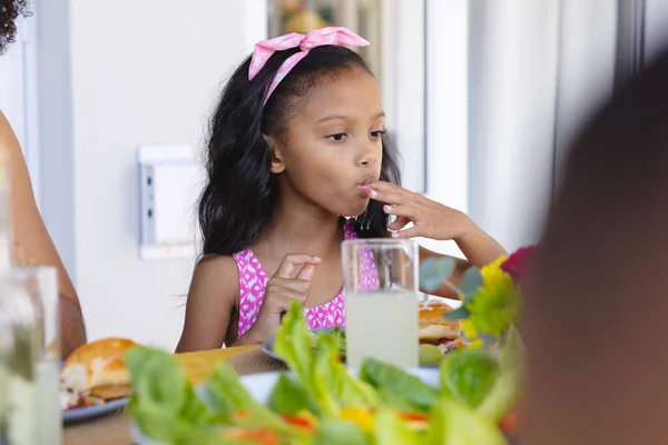 在家里的饭桌上吃午饭的时候 一个戴着粉色帽带的漂亮可爱女孩正在舔着手指 未经改变的食物 生活方式和童年概念 — 图库照片