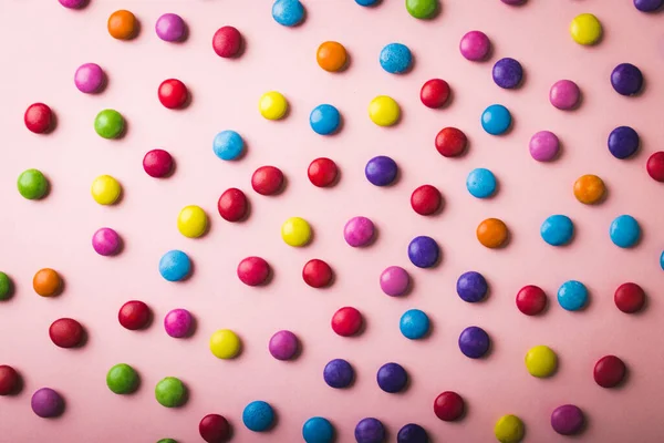 正上方是分散在粉红背景上的多色巧克力糖果 不变的 不健康的饮食和甜食概念 — 图库照片