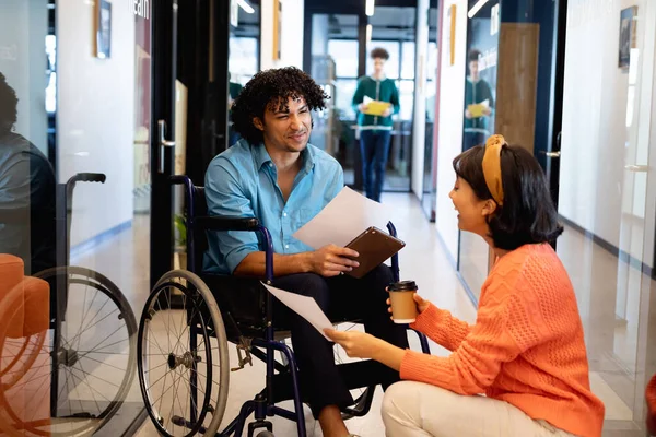 Bizneswoman Dyskutuje Młodym Biznesmenem Siedzącym Wózku Inwalidzkim Korytarzu Biurowym Niezmieniony — Zdjęcie stockowe