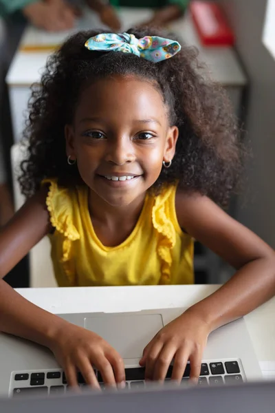 パソコン教室の机でノートパソコンを使ってアフリカ系アメリカ人の小学生の笑顔を描いたポートレート 変化のない教育子供時代学習無線技術学校の概念 — ストック写真