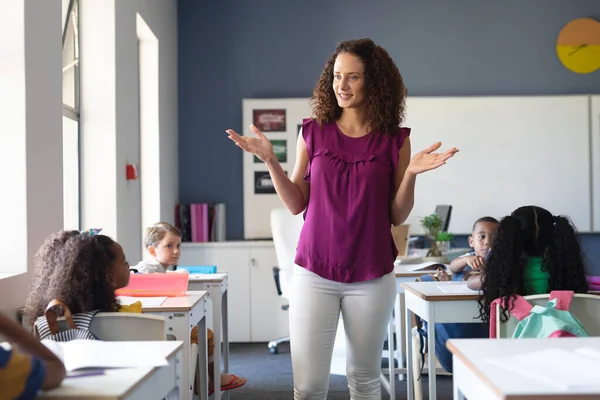 Branco Jovem Professora Gestos Enquanto Ensinava Crianças Multirraciais Elementares Sala — Fotografia de Stock