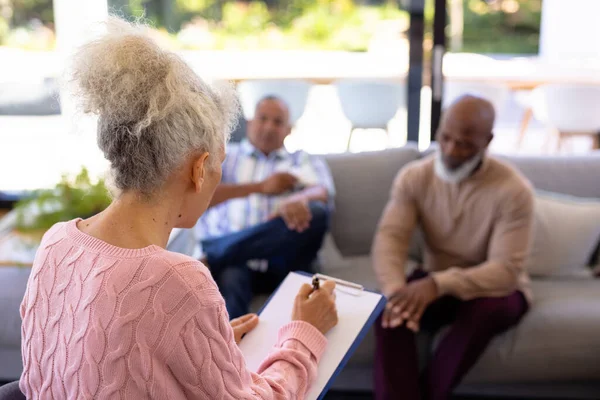 多种族老年妇女与剪贴板听取男子在退休之家分享他们的问题 团体治疗 心理治疗 辅助生活 — 图库照片