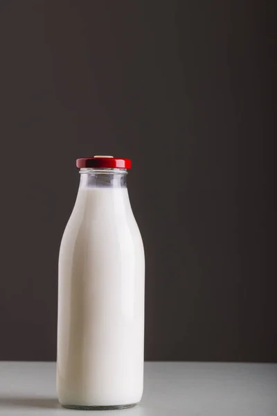 Milk in glass bottle on table against gray background with copy space. unaltered, food, drink, studio shot and healthy food concept.